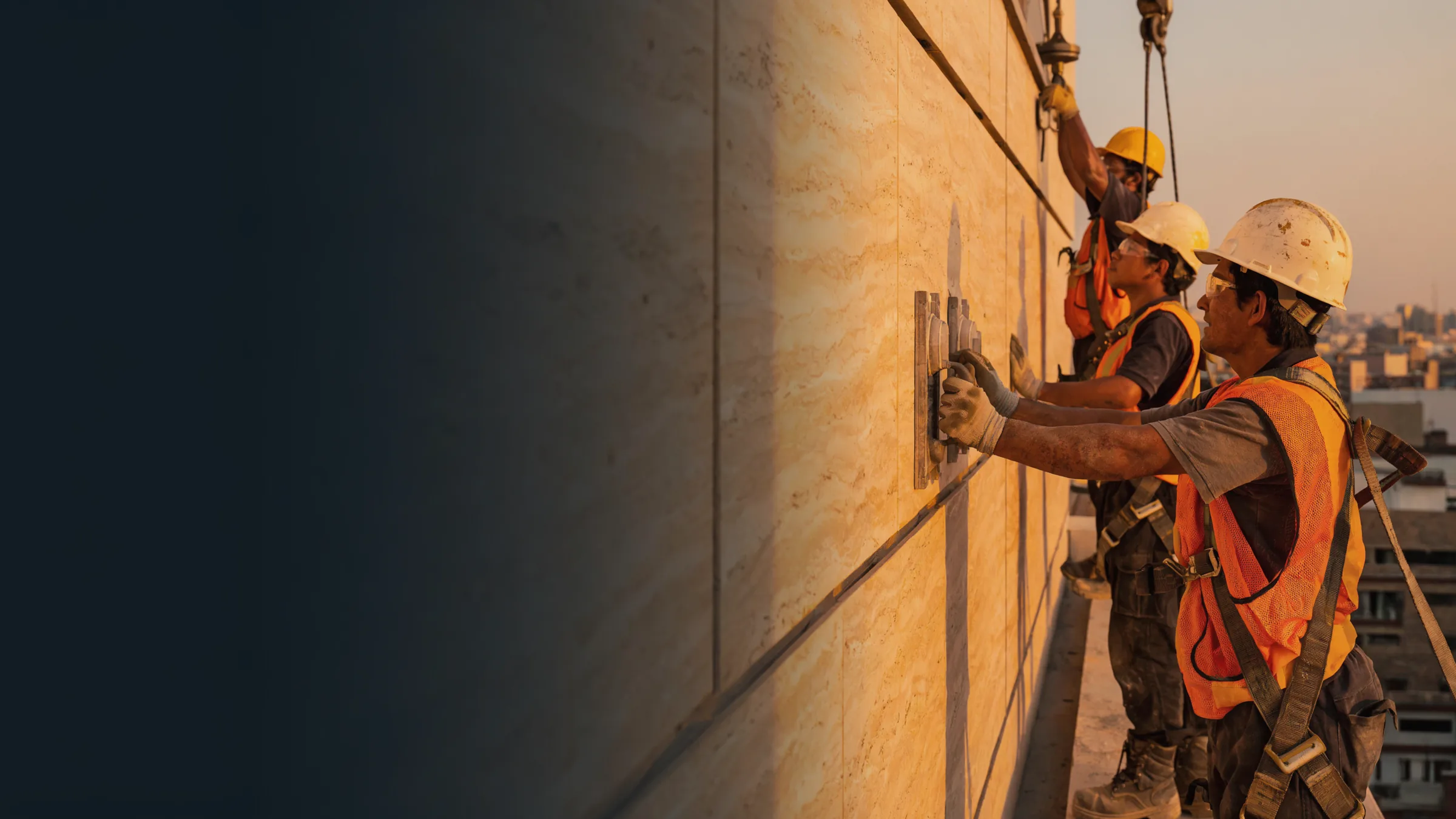 Mexican installers laying travertine slabs on a façade at sunset